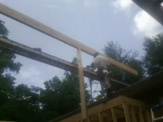 Carpenter setting a ridge beam over a new addition frame — Ice Dam Removal by Roofing Brothers in Rogerson