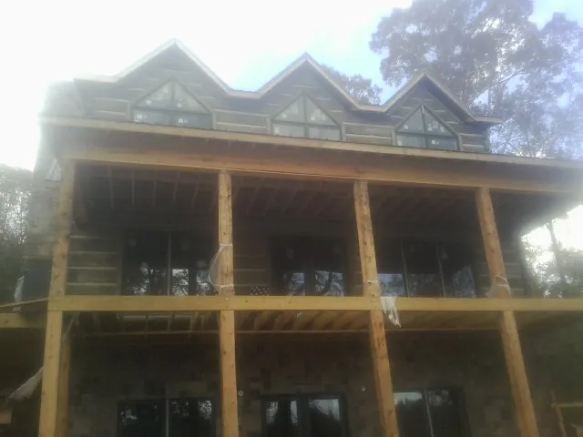 Dormers and porch framing on a large log home under construction — Roof Coating work by our crew in Rogerson