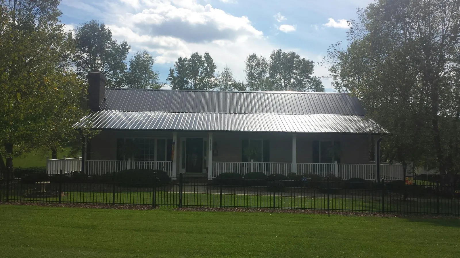 Gray metal roof on a brick ranch with a full width front porch — Gutter Guard Installation work by our crew in Rogerson