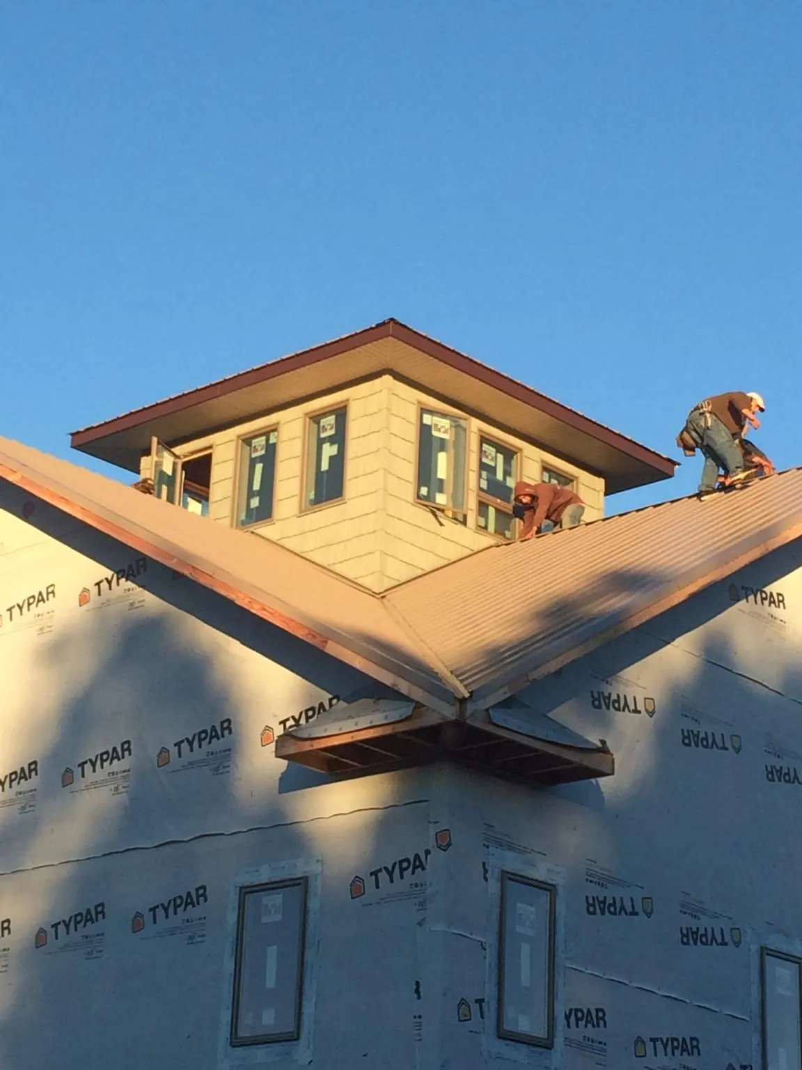 Roofers working around a rooftop cupola on a new metal roof at sunset — Roof Waterproofing in Rogerson by Roofing Brothers
